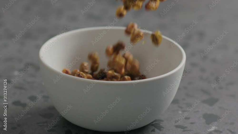 Slow motion dried seaberry falling into white bowl on terrazzo countertop Slow motion dried seaberry falling into white bowl on terrazzo countertop