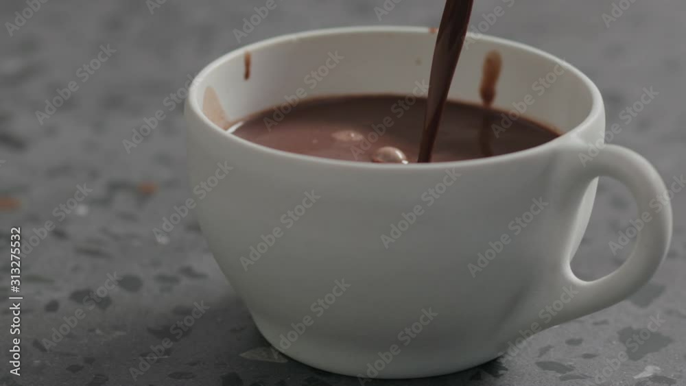 Slow motion pour hot cocoa into white cup on terrazzo countertop Slow motion pour hot cocoa into white cup on terrazzo countertop