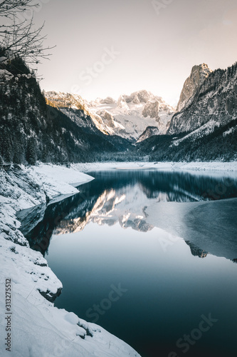 winter view of lake Gosau with fresh snow on majestic mountains  forest and reflection on the lake