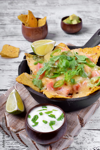 Nachos with cheese, chicken, greenery and vegetables. Mexican cuisine appetizer