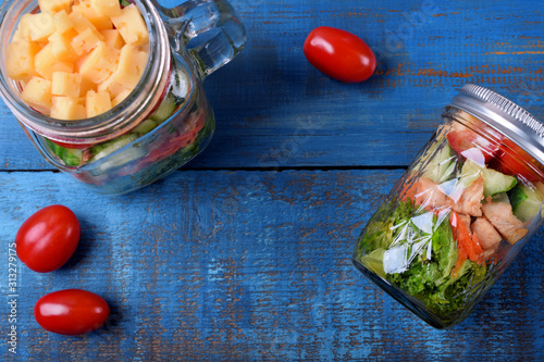 Fotografie Layered salad with cheese, kale, carrot, chicken, cucumbers and cherry tomatoes