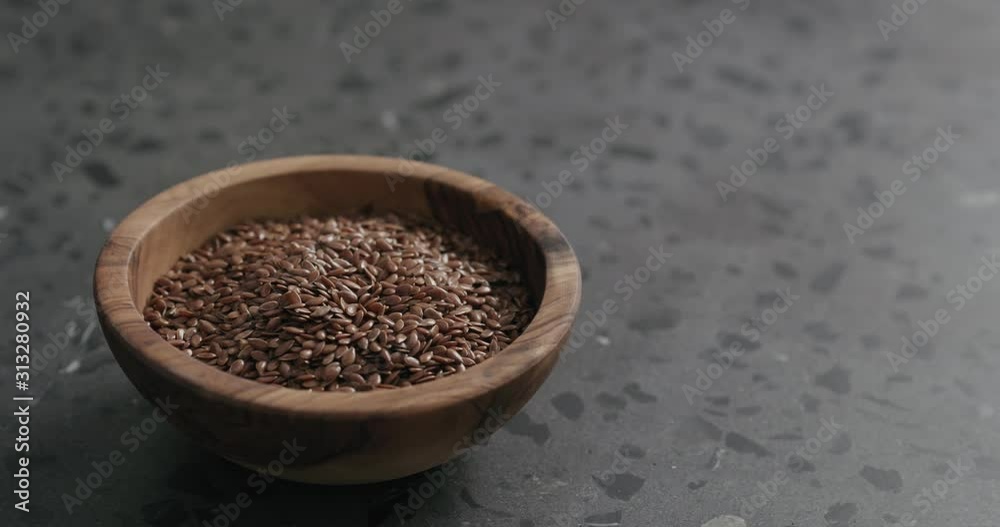 Slow motion handheld shot of flaxseed in olive bowl on terrazzo countertop Slow motion handheld shot of flaxseed in olive bowl on terrazzo countertop