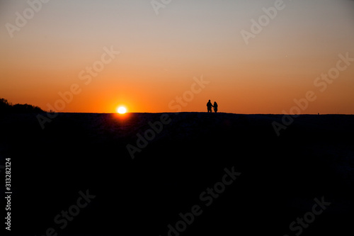 Silhouette of two people on the horizon at sunset