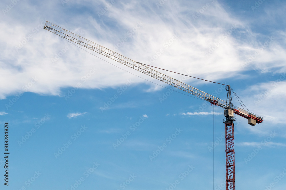 Red crane against blue sky with white clouds. Copy space for text. Red crane against blue sky with white clouds. Copy space for text.
