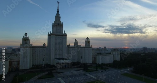 An aerial view of Moscow State University in the evening against dark cloudy sky. The building is rising above the urbanscape, beautifully standing out with its scale and architectural style