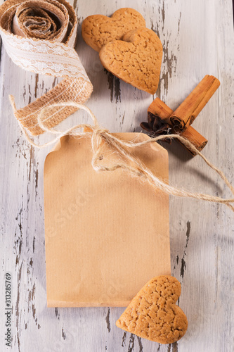 Craft paper mock up card for gift with ginger cookies shaped as hearts on a wooden background. Valentine's day photo