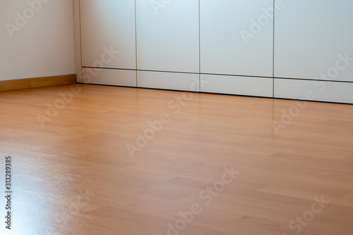 low angle view of wooden laminate flooring in a bright spacious room with wall-to-wall closet