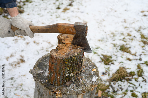 man's hand with an axe chopping wood