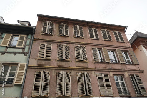 Facade or façade of a historical residential house in Colmar, Alsace, France. The windows have shutters, some of them are closed. the facade is stained by water and time. The house is original state.