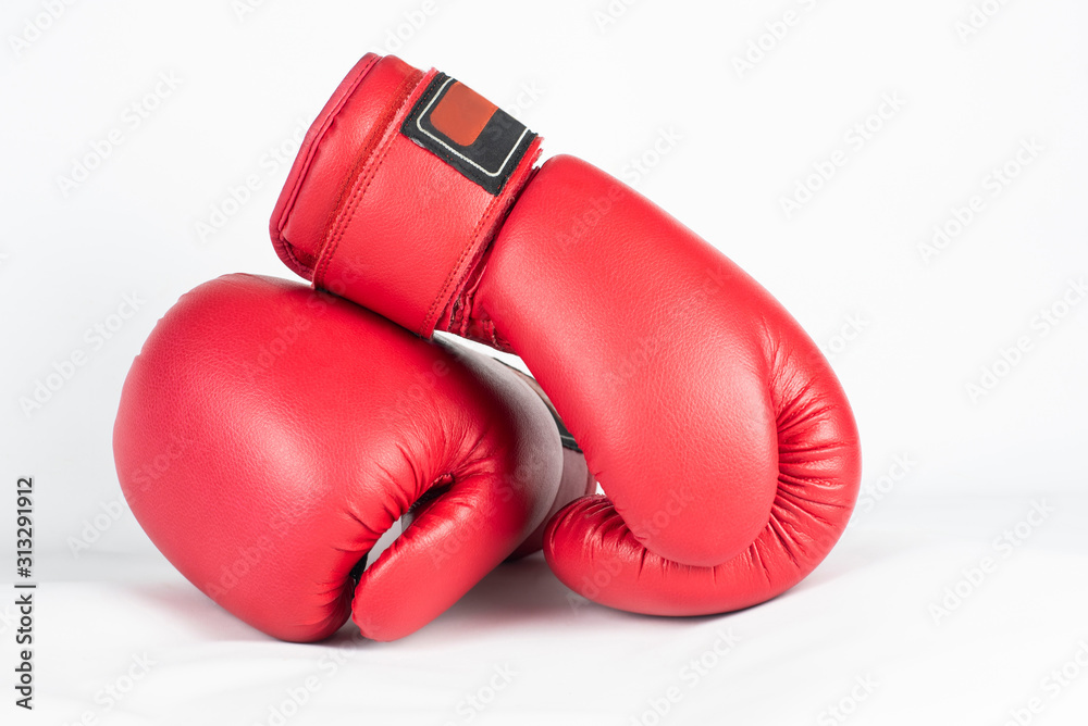Leather red boxing gloves are on top of each other on a light background. Concept of strength