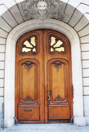 Old fashioned front door entrance, white facade and brown door, Paris, France