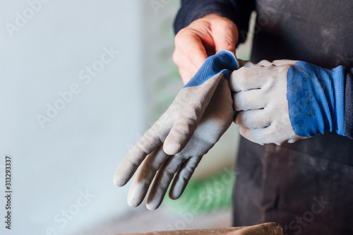 62 year old man working in the fiber shop, puts on gloves