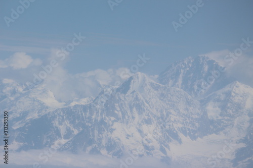 A beautiful photo of a mountain with glacier and snow on it from a height above the clouds