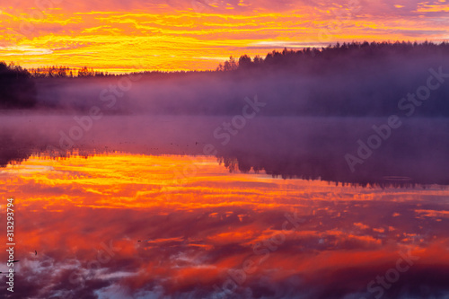 Incredibly red clouds on the sky looking like in fire  reflected in Ozierany lake  Poland.
