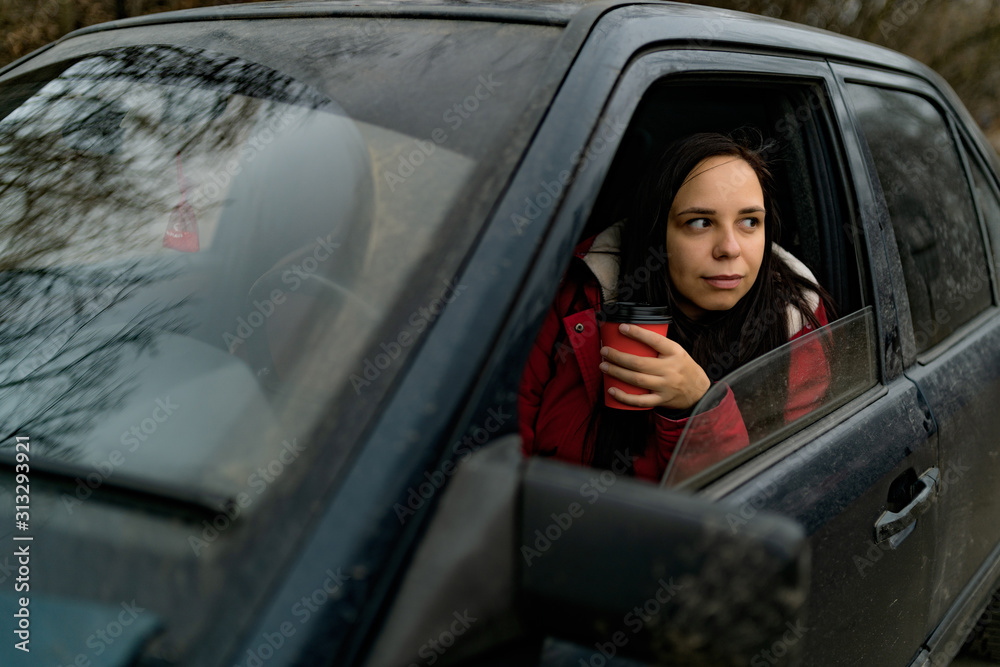 Woman drinks coffee in the car. Young woman drinking coffee while driving her car Woman drinks coffee in the car. Young woman drinking coffee while driving her car