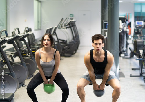 People training in a gym using a kettlebell