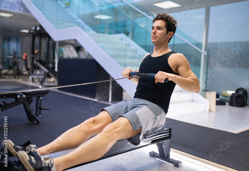 Young man working out on the rowing machine photo