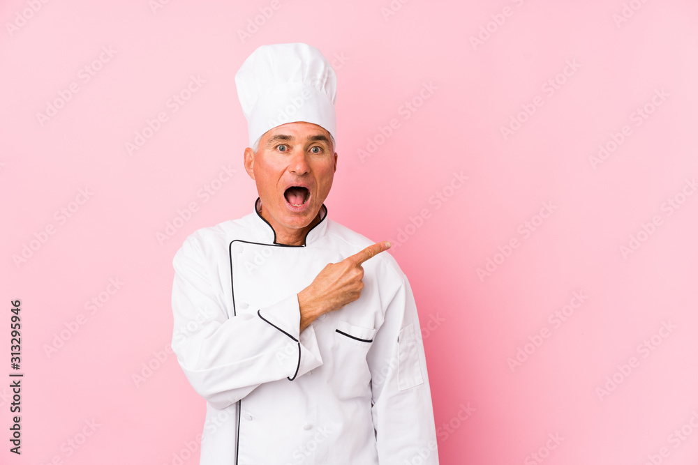 Middle aged cook man isolated pointing to the side Middle aged cook man isolated pointing to the side