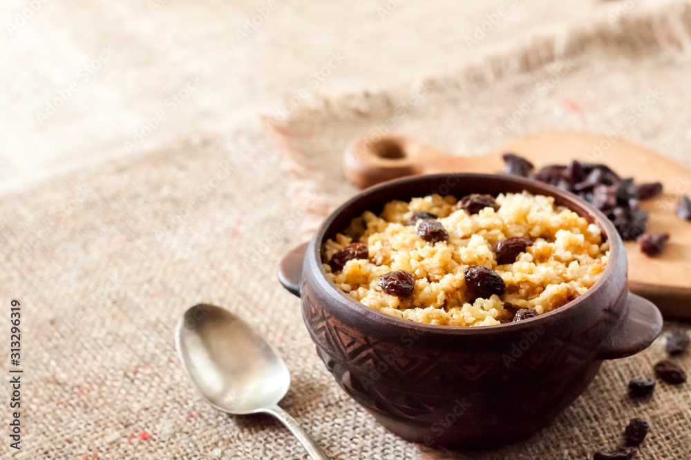 Sweet millet porridge with dark raisins in ceramic rustic bowl Sweet millet porridge with dark raisins in ceramic rustic bowl