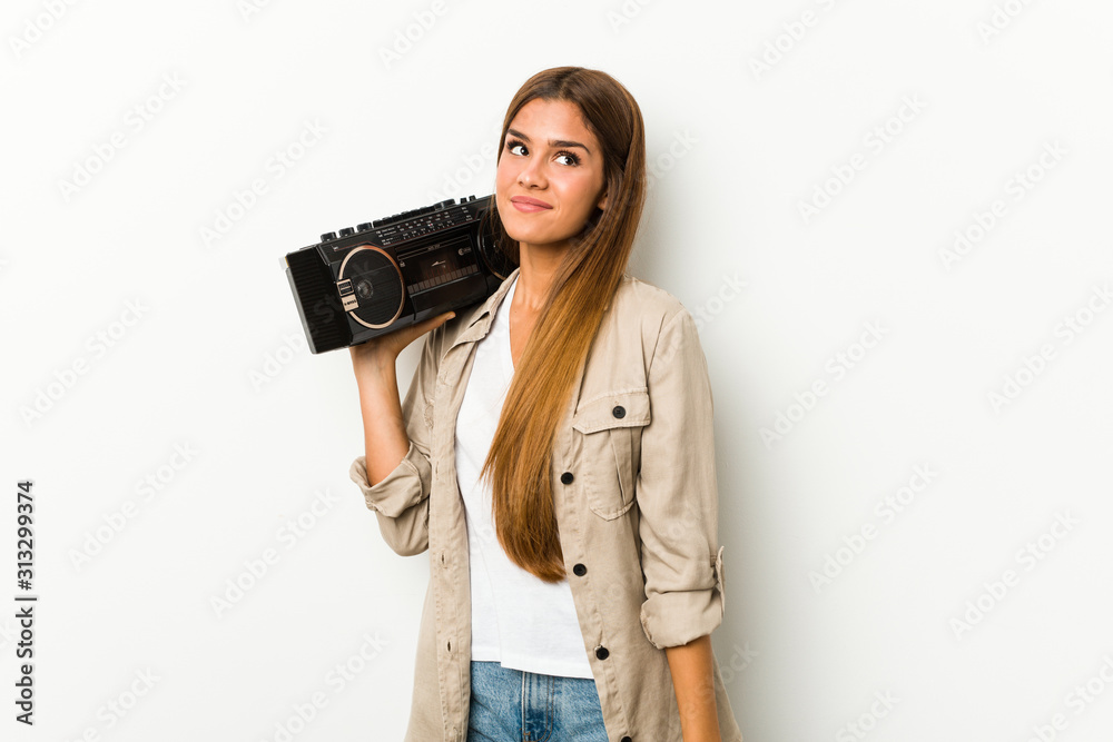 Young caucasian woman holding a guetto blaster dreaming of achieving goals and purposes Young caucasian woman holding a guetto blaster dreaming of achieving goals and purposes
