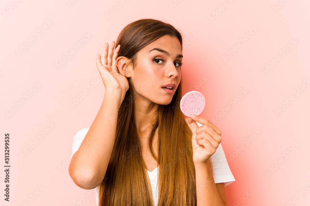 Young caucasian woman holding a facial sponge trying to listening a gossip. Young caucasian woman holding a facial sponge trying to listening a gossip.