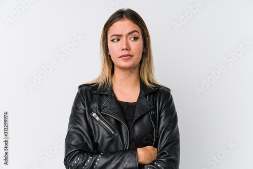 Young caucasian woman wearing a black leather jacket confused, feels doubtful and unsure.