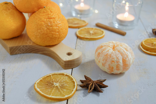 Tangerines, decor of dried citrus fruits, candles are lokated on a painted blue wooden surface. photo
