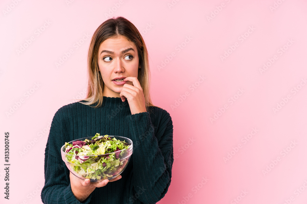 Young caucasian woman holding a salad isolated relaxed thinking about something looking at a copy space.
