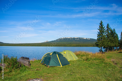 family outing. tent on the shore of a mountain lake. Rest and travel in the summer. ecological tourism in the fresh air