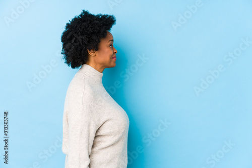 Middle aged african american woman against a blue background isolated gazing left, sideways pose.