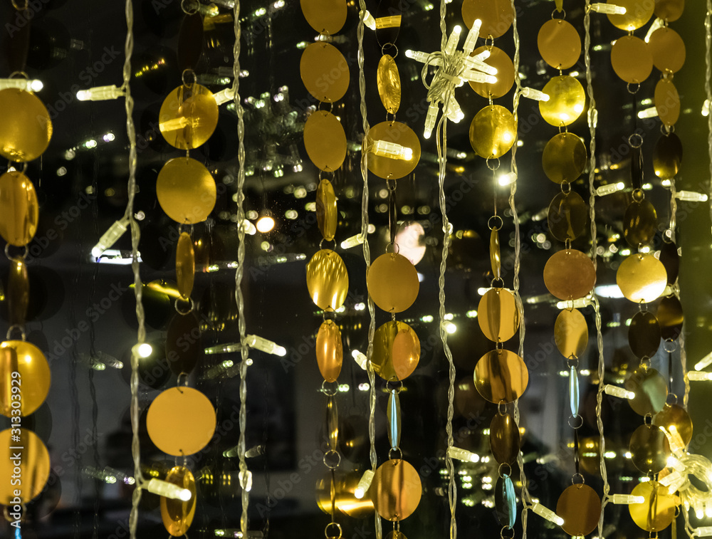 Golden balls in garlands decorate the interior. Festive attire in celebration of the New Year and Christmas. Gold and black abstract background Golden balls in garlands decorate the interior. Festive attire in celebration of the New Year and Christmas. Gold and black abstract background