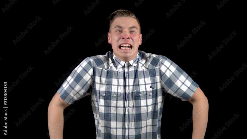 The young man is screaming. A man screams strongly in a shirt on a black background The young man is screaming. A man screams strongly in a shirt on a black background
