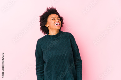 Middle aged african american woman against a pink background isolated relaxed and happy laughing, neck stretched showing teeth.