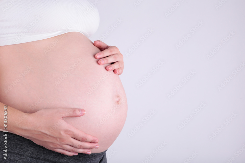 A cute pregnant belly on a grey background A cute pregnant belly on a grey background