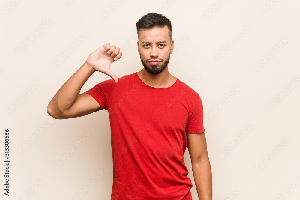 Young south-asian man showing a dislike gesture, thumbs down. Disagreement concept. Young south-asian man showing a dislike gesture, thumbs down. Disagreement concept.