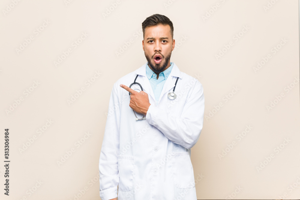 Young south-asian doctor man pointing to the side Young south-asian doctor man pointing to the side