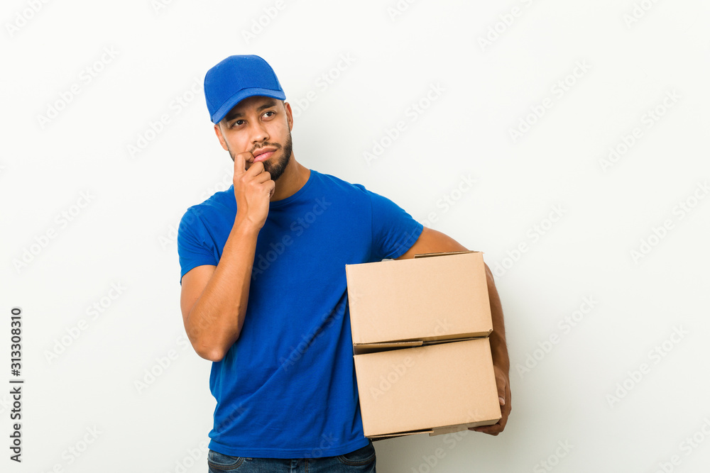 Young south-asian delivery man relaxed thinking about something looking at a copy space. Young south-asian delivery man relaxed thinking about something looking at a copy space.