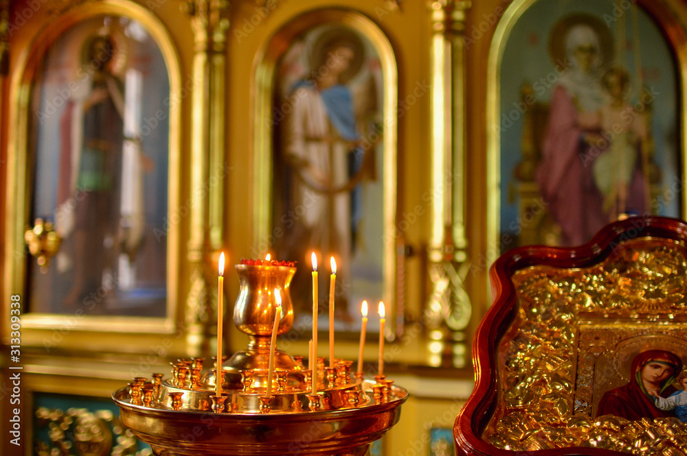 Icon of Jesus in a wooden frame. Candles are burning in the temple near the altar. Temple.