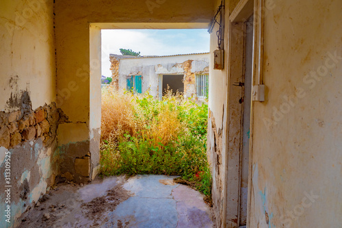 Abandoned house. Destroyed building. Houses without owners. Abandonment. Crumbling walls and weeds in the front garden. No one lives in the houses. © Grispb