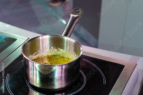The metal ladle on the stove. The cooking of the sauce. Cheese sauce for spaghetti. Recipes of national dishes. Equipment of cafes and restaurants. Varied menu.