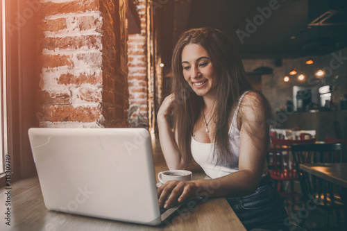 Business woman working on a laptop and drinking coffee in a cafe.