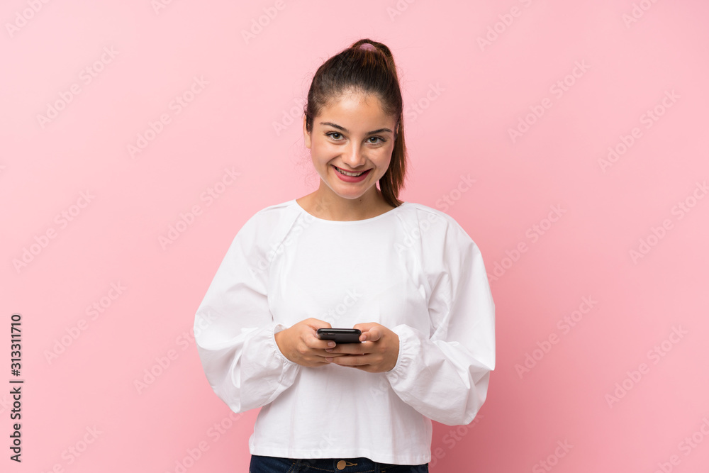 Young brunette girl over isolated pink background sending a message with the mobile Young brunette girl over isolated pink background sending a message with the mobile