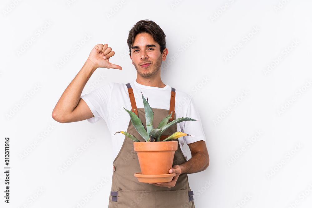 Young caucasian gardener man holding a plant isolated feels proud and self confident, example to follow. Young caucasian gardener man holding a plant isolated feels proud and self confident, example to follow.