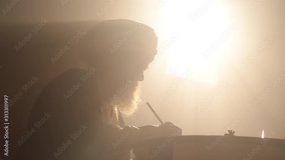Old islamic man with bear and turban studying and writing