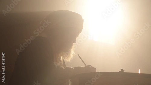 Old islamic man with bear and turban studying and writing
