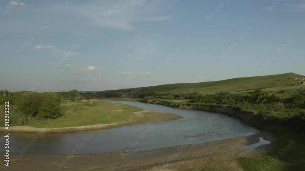 Gliding aerial shot of nature vista in Alberta Canada featuring a winding river