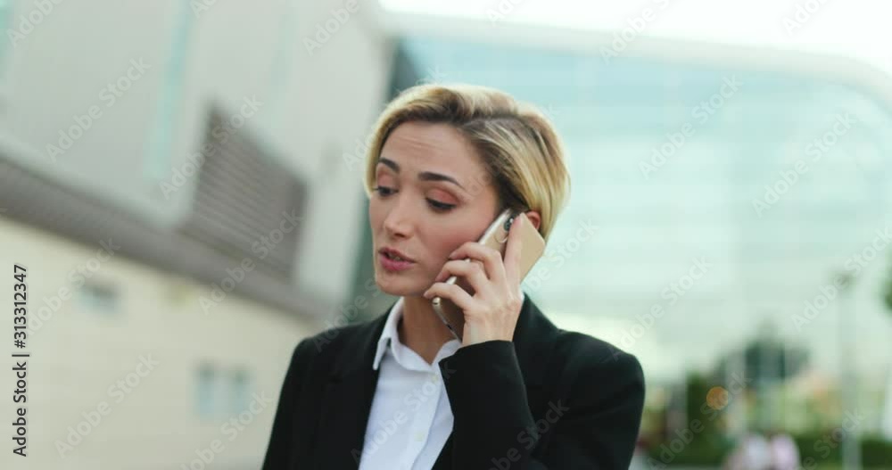 Young attractive Caucasian woman talking on the mobile phone and discussing her business or work issues. Outside. Close up. Young attractive Caucasian woman talking on the mobile phone and discussing her business or work issues. Outside. Close up.