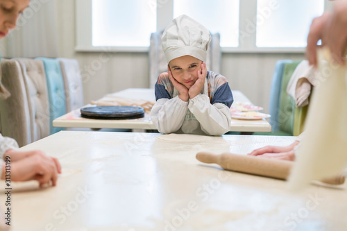 Cook boy. Little boy is a cook in flour in a white hat and apron in the kitchen