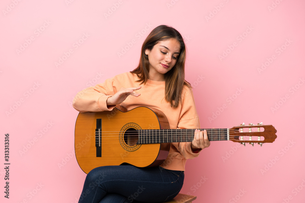 Young brunette girl with guitar over isolated pink background Young brunette girl with guitar over isolated pink background