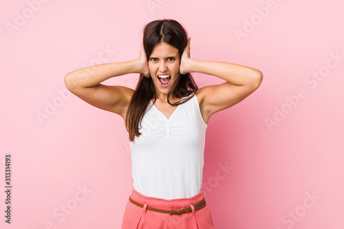 Young cute woman covering ears with hands trying not to hear too loud sound.
